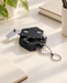 Compact black multitool with a silver ball chain on an ivory desk.
