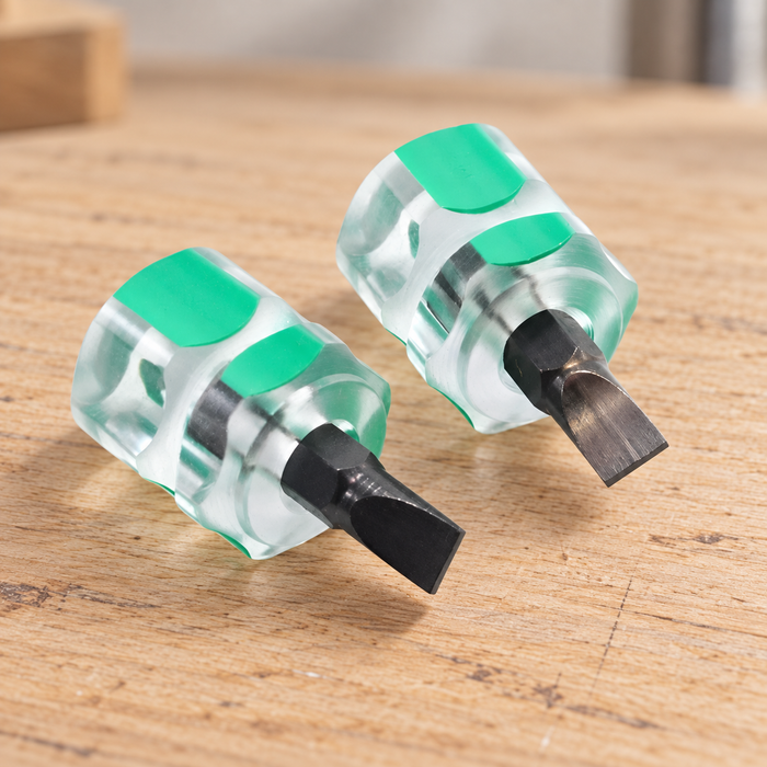 Two clear and mint-green handled precision screwdrivers on a wooden workbench.