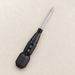 Black screwdriver with a silver shaft resting on an ivory workbench.