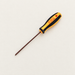 Orange and black hex screwdriver lying diagonally on a softly lit ivory workbench.