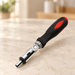 Black and red articulated ratchet screwdriver on a pale stone surface