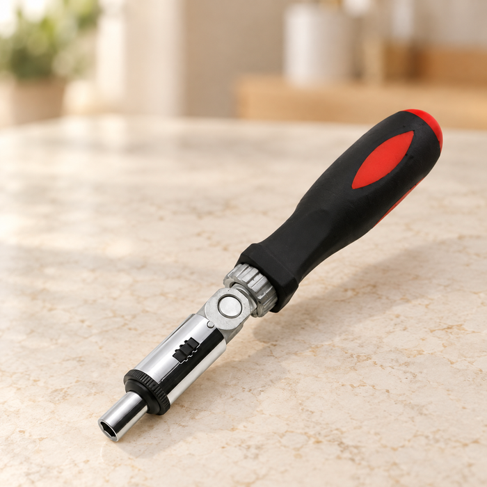 Black and red articulated ratchet screwdriver on a pale stone surface