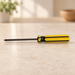 Yellow and black Phillips screwdriver resting horizontally on pale stone