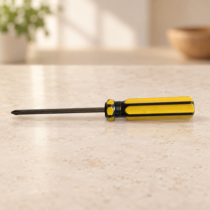 Yellow and black Phillips screwdriver resting horizontally on pale stone