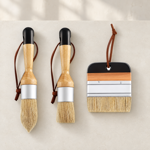 Three wooden handled paint brushes arranged on a warm ivory surface.