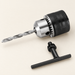 Drill chuck with a twist bit and black T-shaped key on an ivory surface