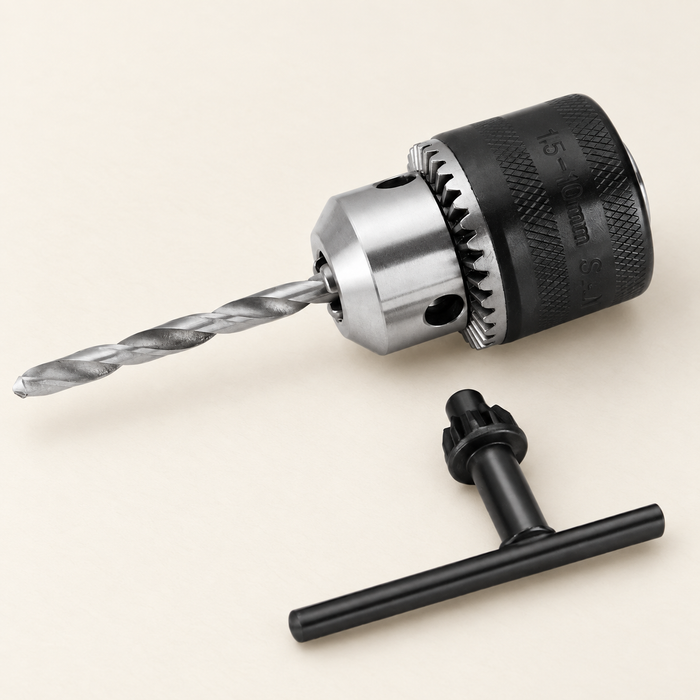 Drill chuck with a twist bit and black T-shaped key on an ivory surface