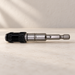 Silver and black screwdriver bit holder lying on a pale work surface