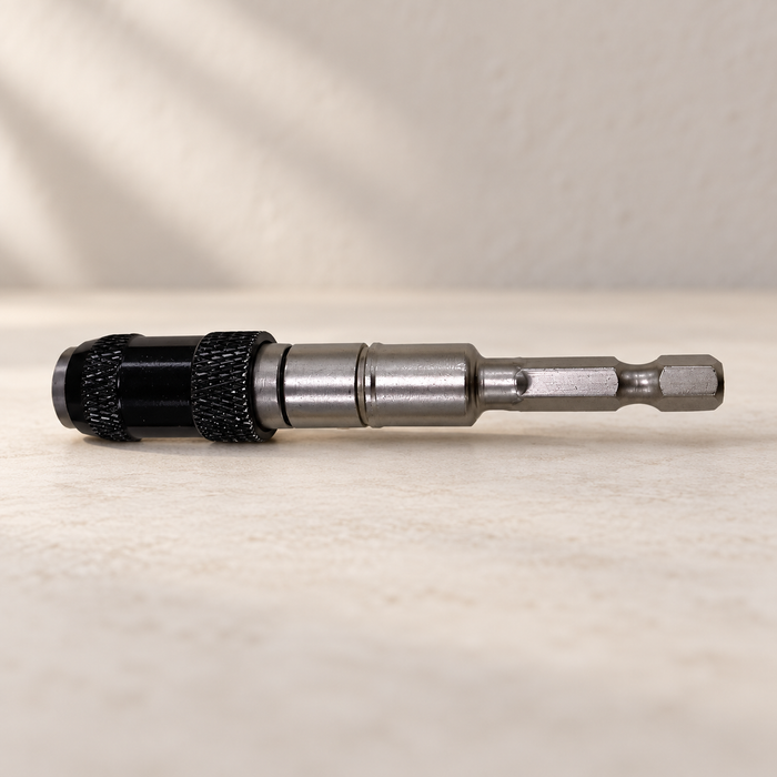 Silver and black screwdriver bit holder lying on a pale work surface