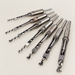 Seven square-hole woodworking drill assemblies on an ivory work surface.