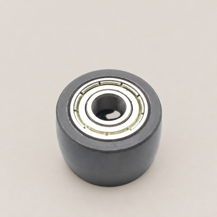 Small dark roller with a metal bearing on an ivory workbench.