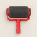 Black foam paint roller with a red frame and handle on an ivory workbench.