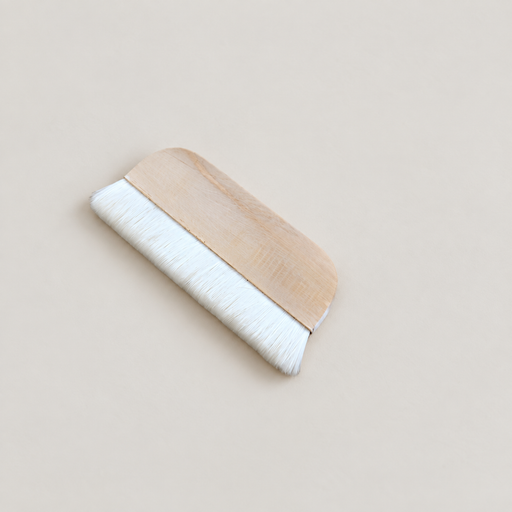 Wide wooden wool paint brush on an ivory surface