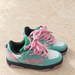 Pair of turquoise and pink sneakers with rope laces on ivory stone.