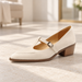 Cream T-bar pump with block heel on an ivory stone floor