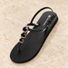 Black slingback sandal with three oval jewel details on pale limestone.