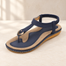 Navy and tan sandal with gold ring detail on an ivory surface