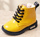 Yellow lace-up boot with black sole on an ivory stone surface