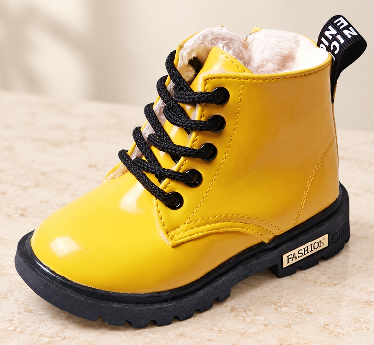 Yellow lace-up boot with black sole on an ivory stone surface