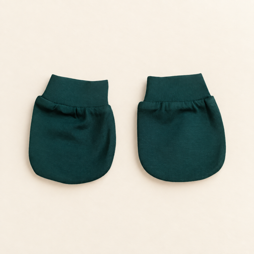 Pair of forest green baby mittens on ivory tabletop