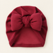 Burgundy baby bow beanie on ivory tabletop