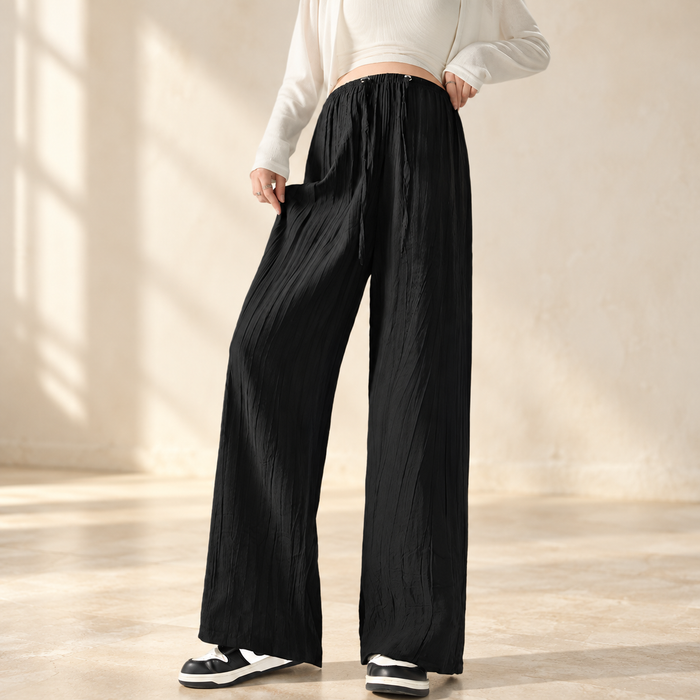 Black textured wide-leg trousers worn in a warm ivory interior