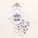White baby bodysuit, crown-pattern trousers and matching knotted hat on an ivory surface