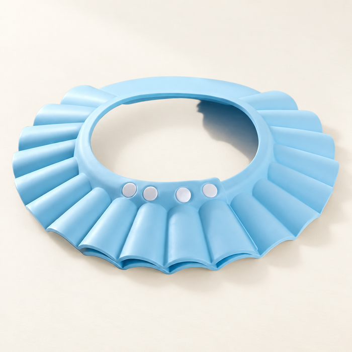 Light blue adjustable shower cap with four white snaps and a scalloped brim on an ivory surface.