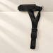 Black padded adjustable dog muzzle with woven straps and silver ring on an ivory surface.